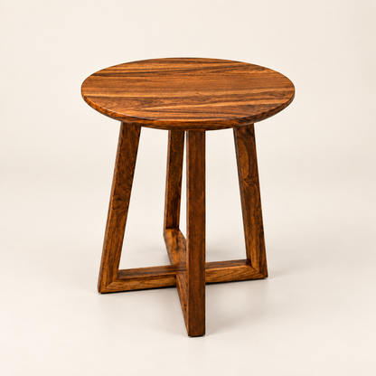 A round wooden side table with a rich dark brown grain pattern, featuring a thick circular top and four angled legs that intersect at the base, photographed on a clean off-white background.
